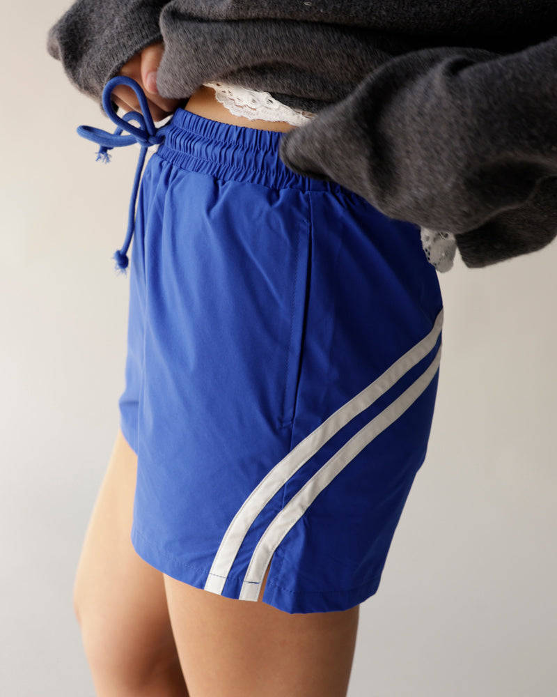 Royal blue athletic track shorts with white side stripes and elastic drawstring waist