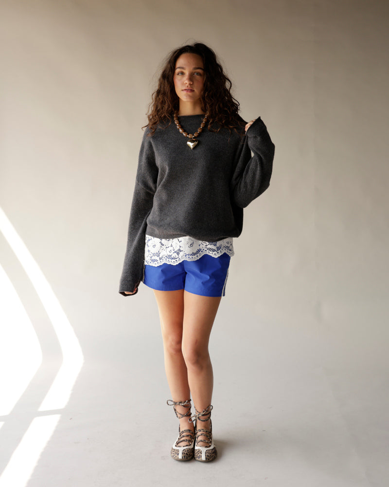 Bright blue track shorts with white lace hem trim, paired with grey oversized sweater