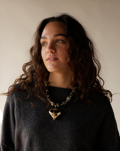 Chunky sheer grey bead cord necklace featuring a large gold heart charm and adjustable 2-inch extension. A bold, trendy statement piece for any look.