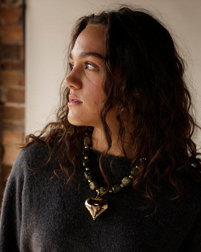 Chunky dark stone beaded necklace with large gold puffy heart pendant on model