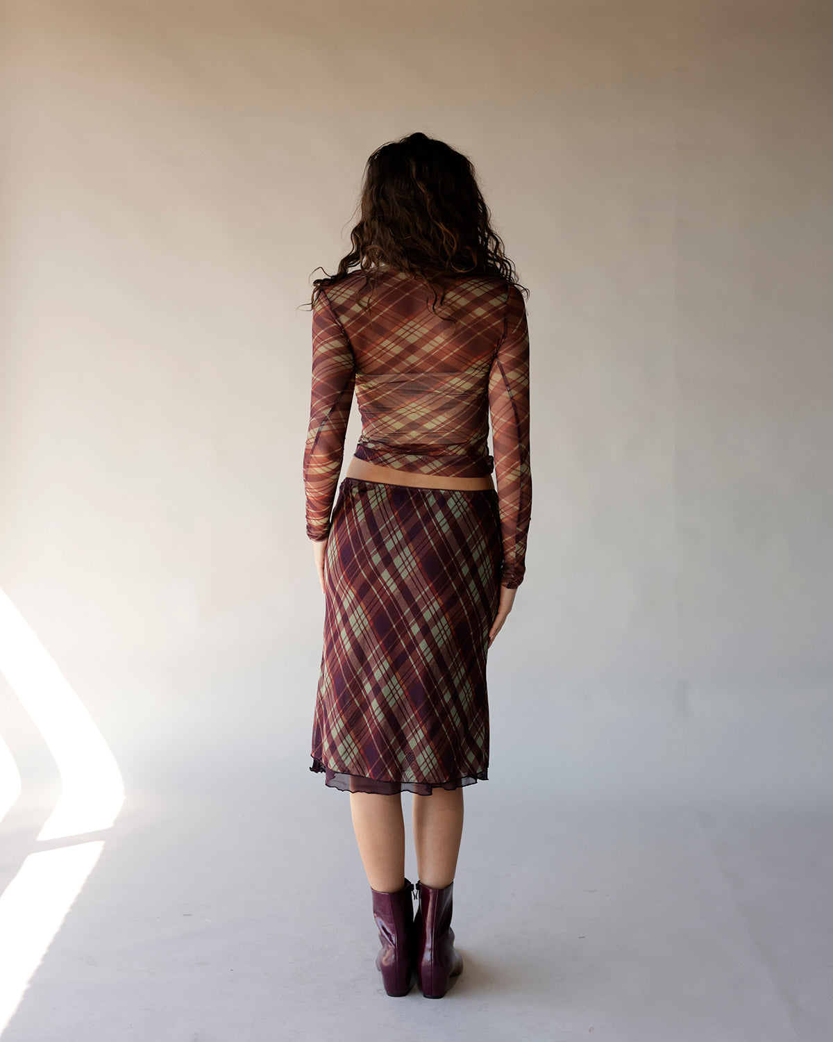 Brown plaid mesh long sleeve crop top worn with matching midi skirt, back view