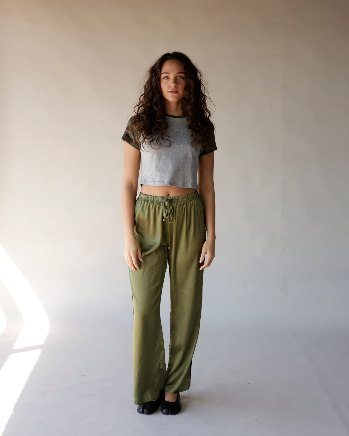 Olive green satin track pants with elastic drawstring waist and relaxed wide leg fit