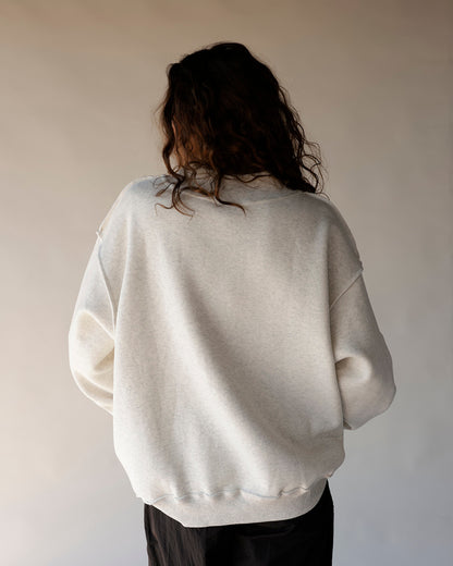 Oversized light gray mock neck sweatshirt shown from the back on a model