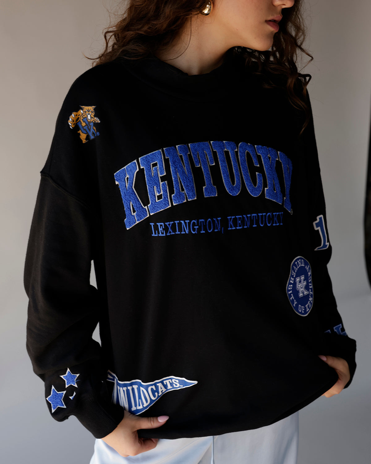 Black Kentucky Wildcats crewneck sweatshirt with blue embroidered text and patches