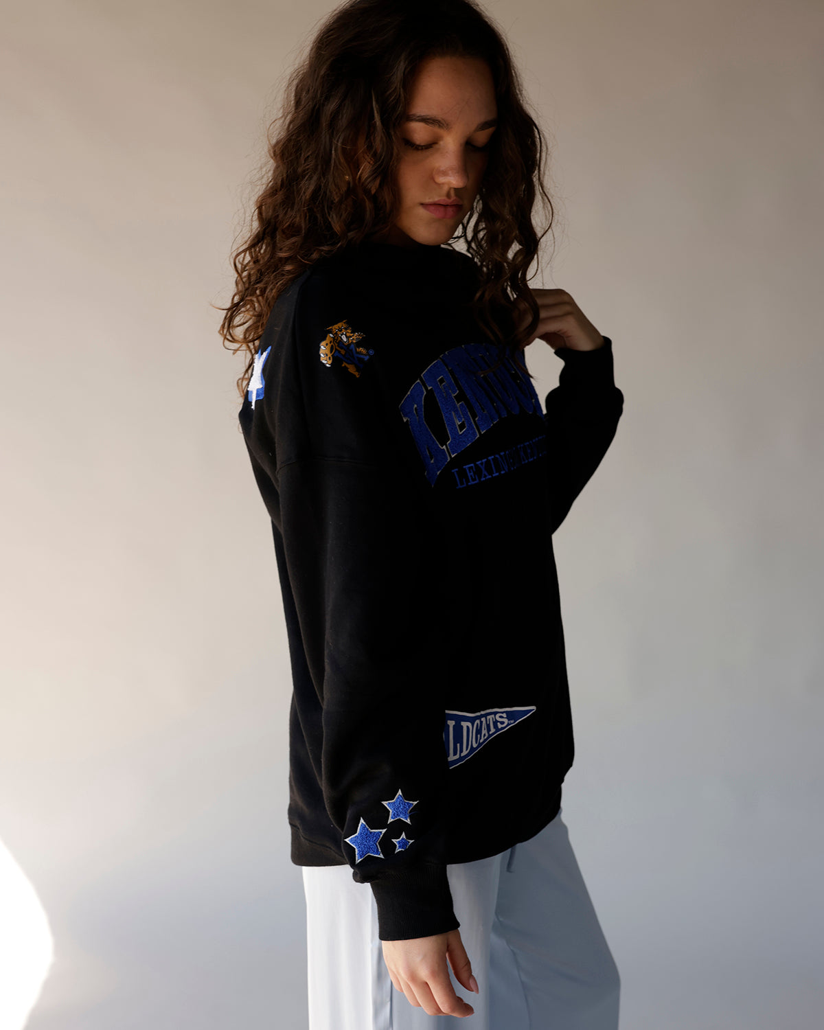 Black Kentucky Wildcats crewneck sweatshirt with blue graphics, stars, and pennant patch
