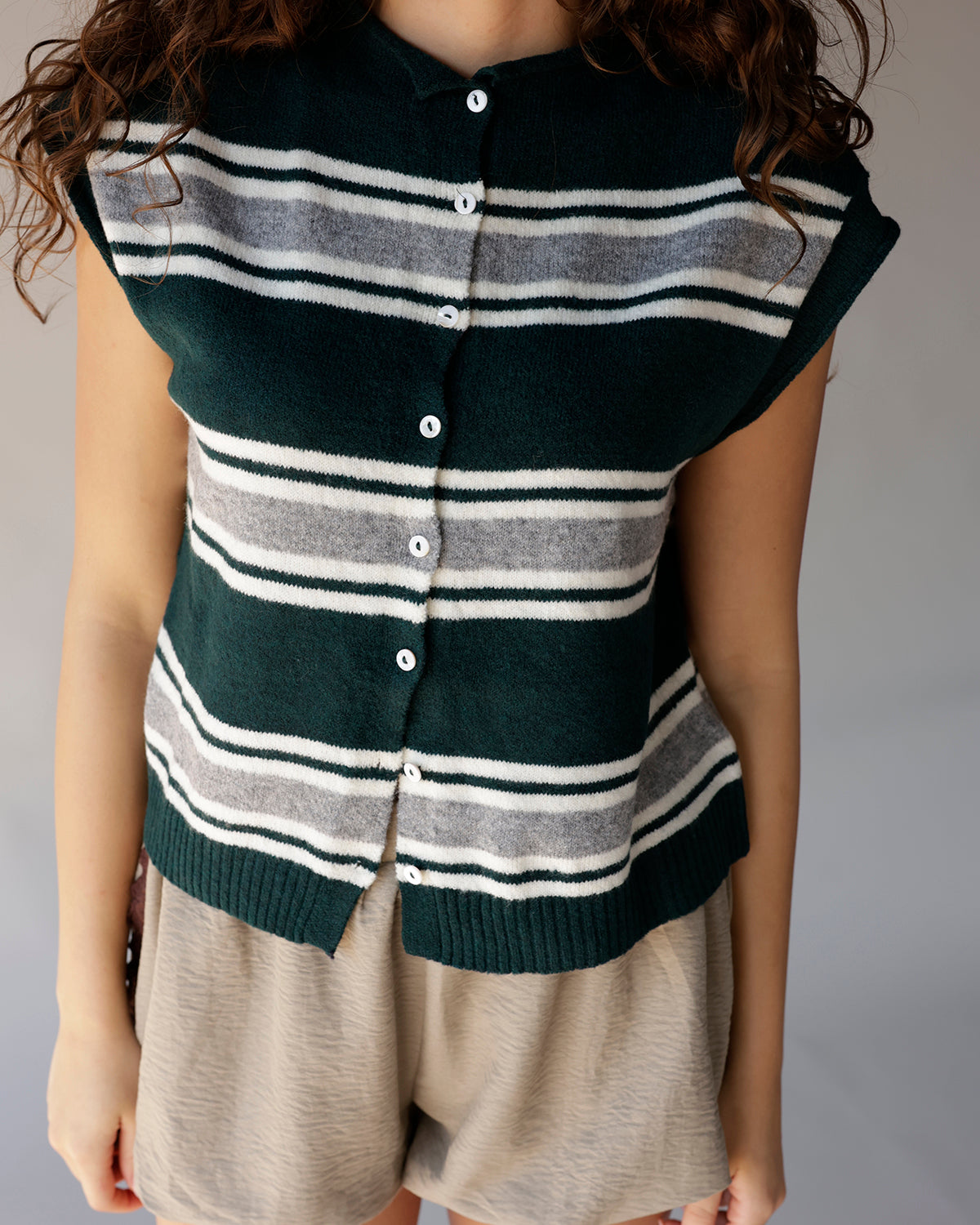 Dark green striped knit cardigan vest with white buttons and ribbed hem