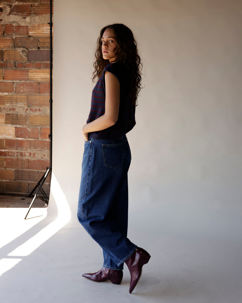 Navy striped sleeveless sweater vest with burgundy stripes, worn with wide-leg jeans