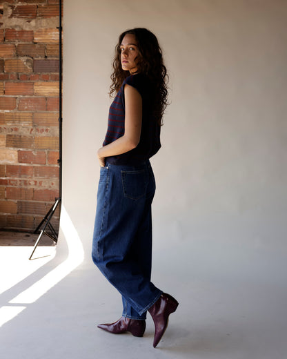 Navy striped sleeveless sweater vest with burgundy stripes, worn with wide-leg jeans