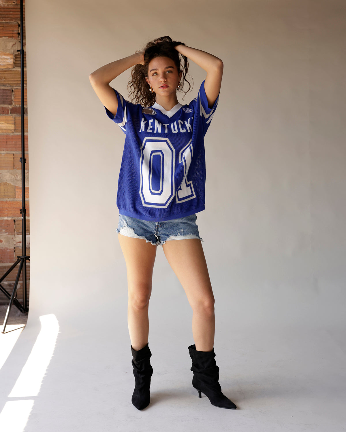 Blue Kentucky Wildcats football jersey number 01 styled with denim shorts and black boots