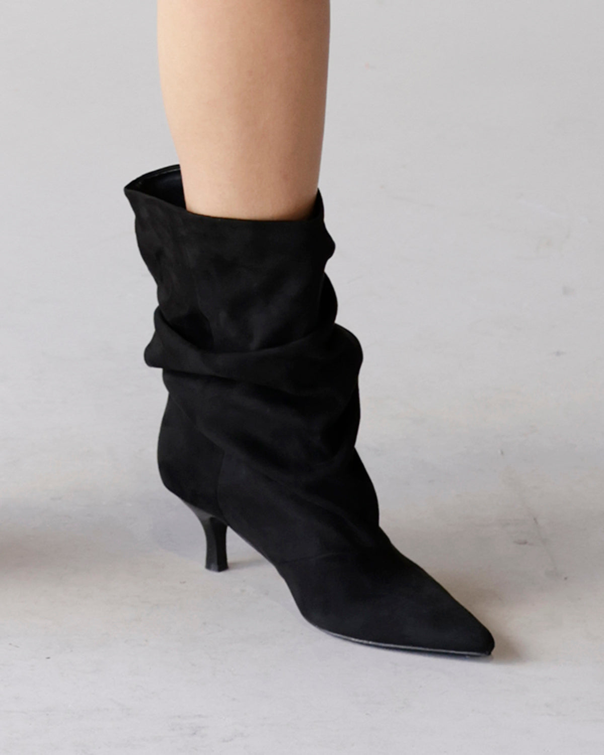 Black suede slouch bootie with kitten heel and pointed toe on leg