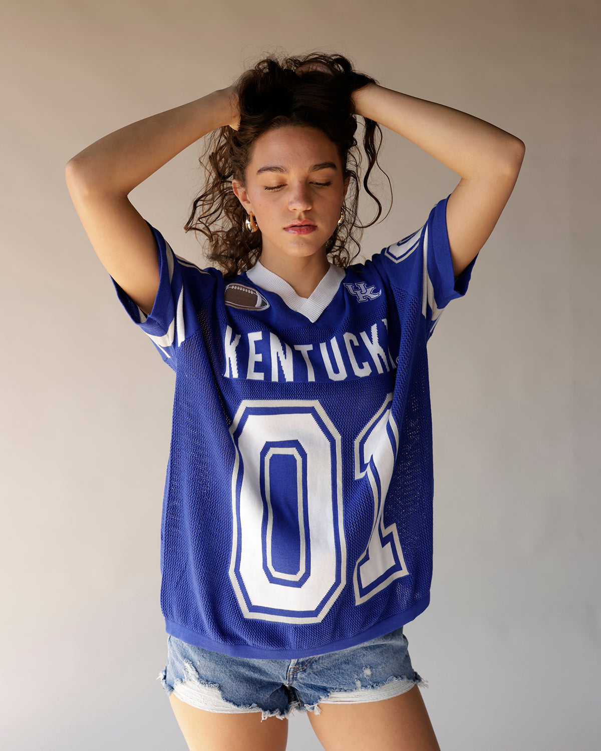 Women's blue Kentucky Wildcats football jersey with number 02, worn with denim shorts