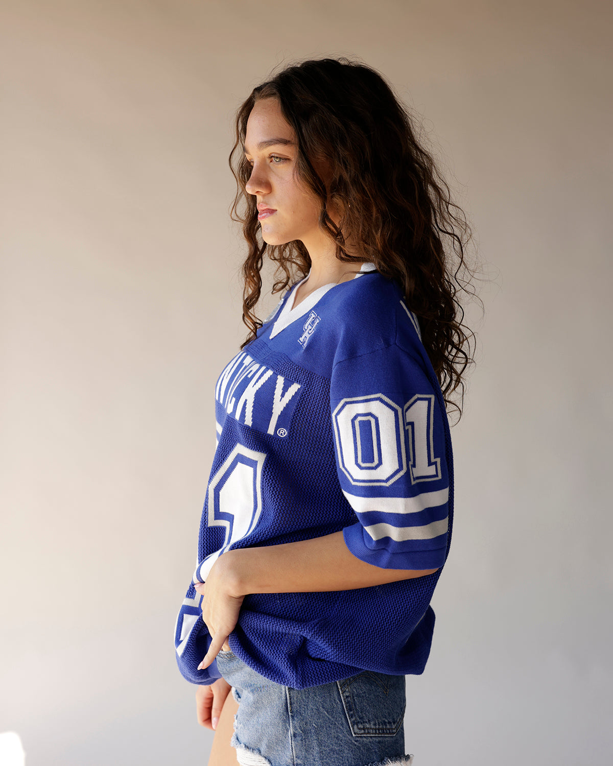 Blue Kentucky Wildcats football jersey with white lettering and number, worn by model