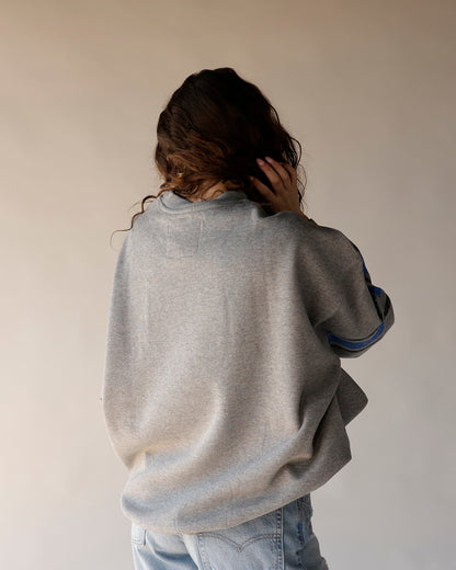 Gray crewneck sweatshirt with blue stripe sleeve detail, back view, worn with jeans
