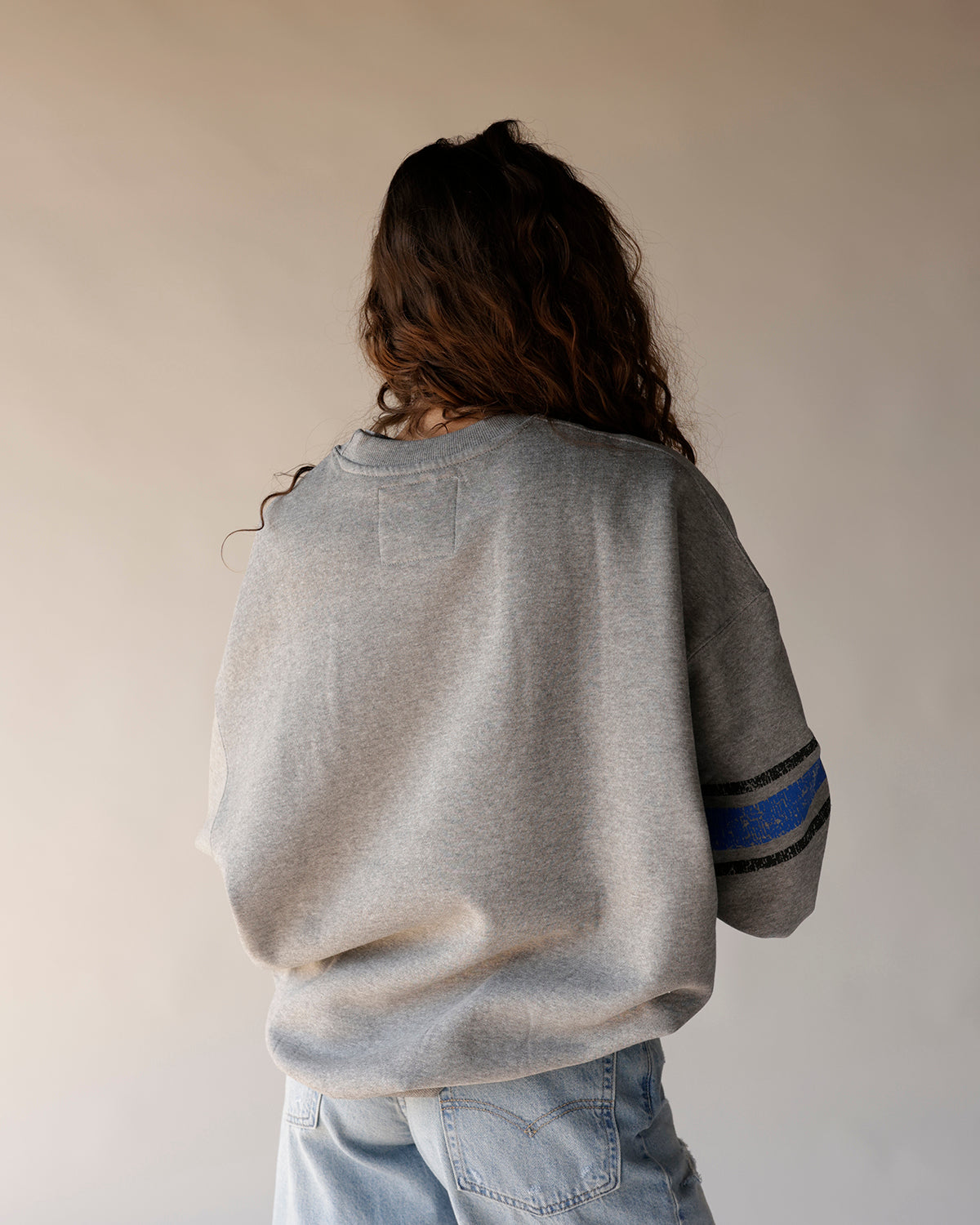 Gray oversized crewneck sweatshirt with blue and black stripe detail on sleeve