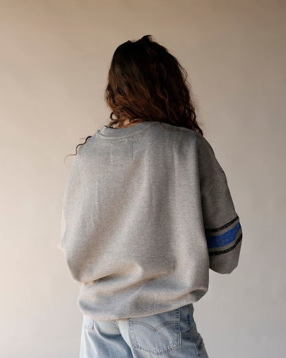 Gray oversized crewneck sweatshirt with blue and black stripe detail on sleeve