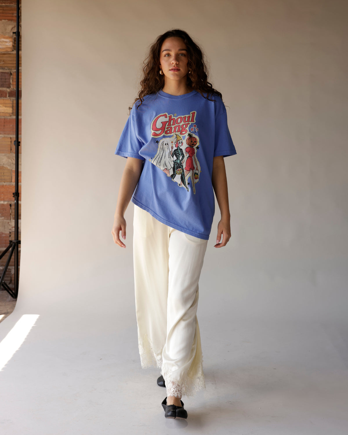 Oversized blue graphic tee with Ghoul Gang Halloween print, worn with cream wide-leg pants