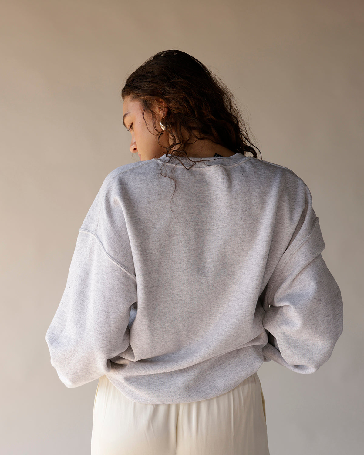 Heather gray oversized crewneck sweatshirt, back view, worn with cream pants.