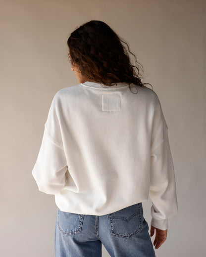 White oversized crewneck sweatshirt back view, paired with light wash blue jeans