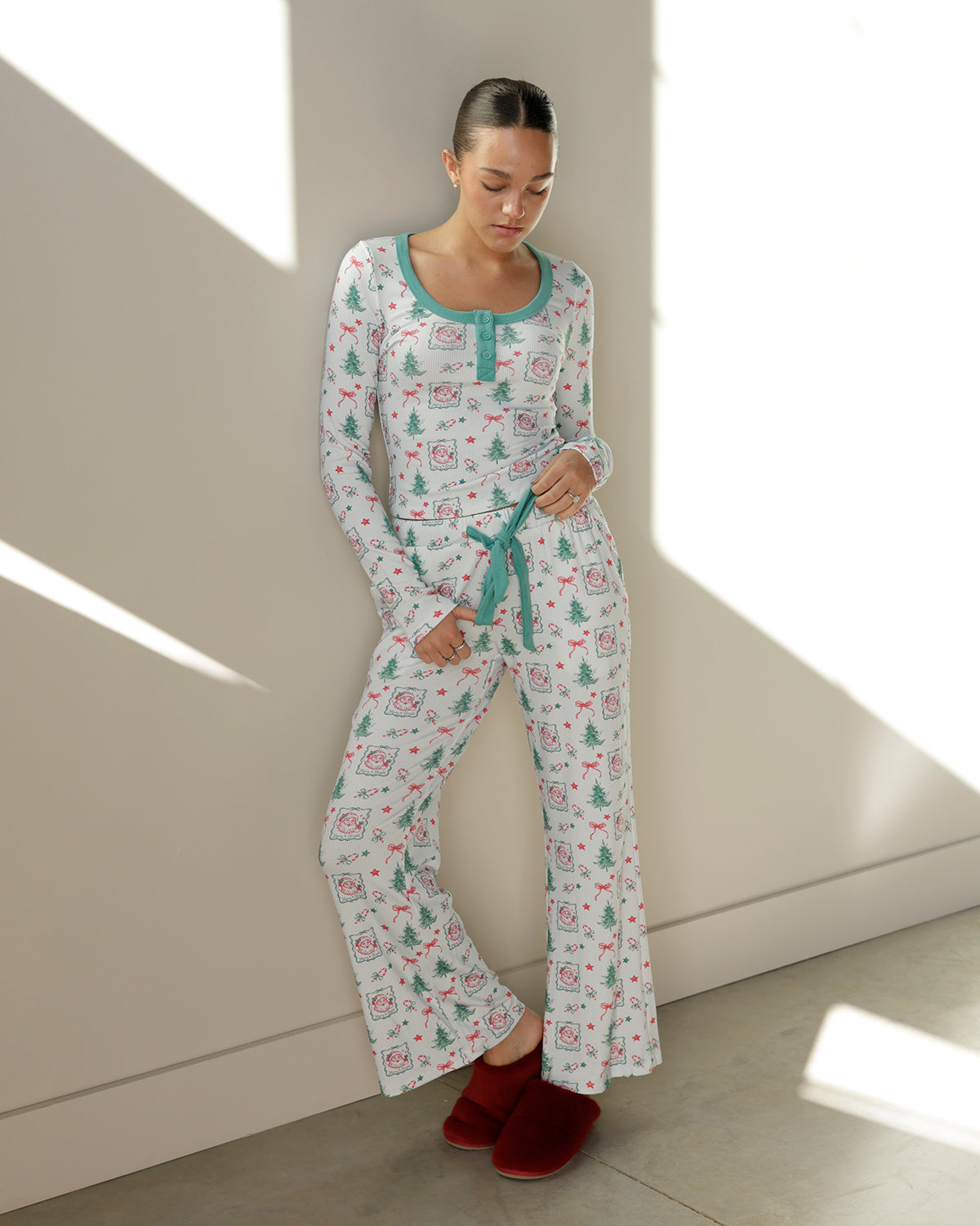 women's ivory christmas pajama set with vintage santa faces, green christmas trees, red bows, mint green henley neckline and matching tie-waist pants.