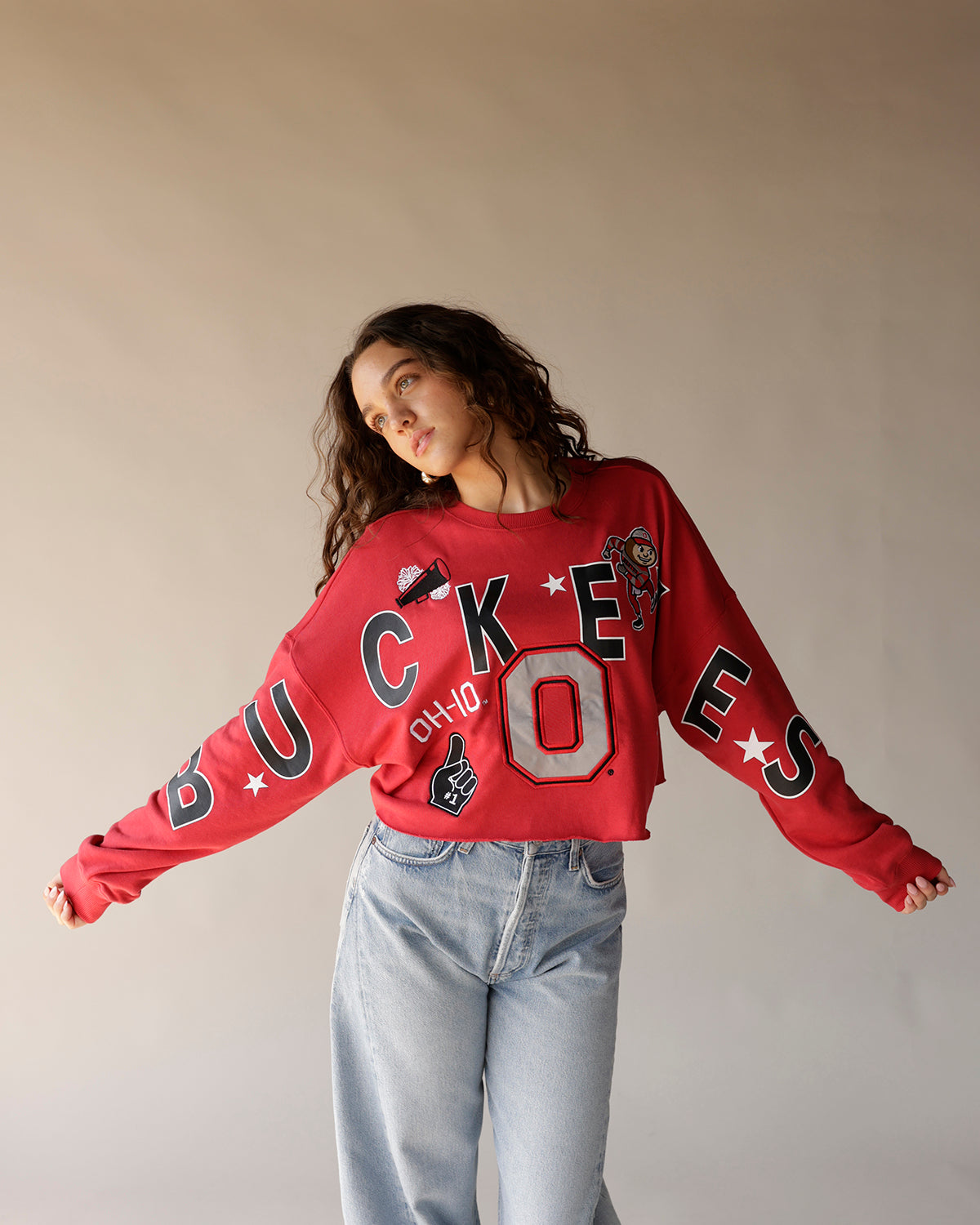 Red cropped Ohio State Buckeyes sweatshirt with bold graphics, worn with light blue jeans.