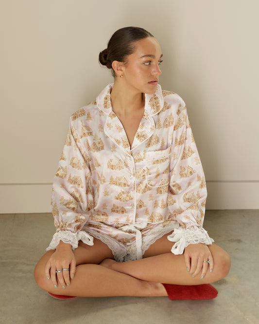 peach love blush pink gingerbread christmas pajama set featuring a long sleeve button-front top, holiday house print and matching lace-trimmed shorts.