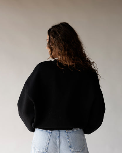 Black oversized crewneck sweatshirt back view, paired with light wash jeans