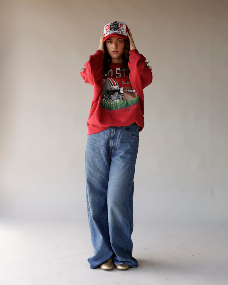 Woman wearing red Ohio State graphic sweatshirt, wide-leg jeans, and red trucker hat