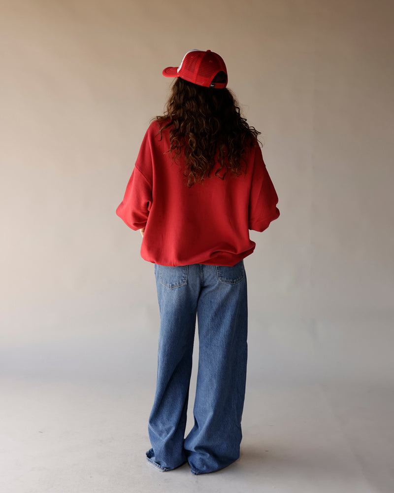 Women's oversized red sweatshirt with wide-leg blue jeans and red trucker cap