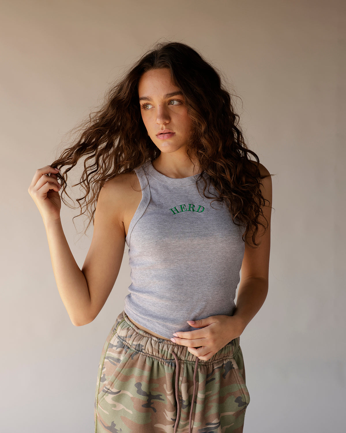Gray racerback tank top with green HERD embroidery, paired with camo joggers