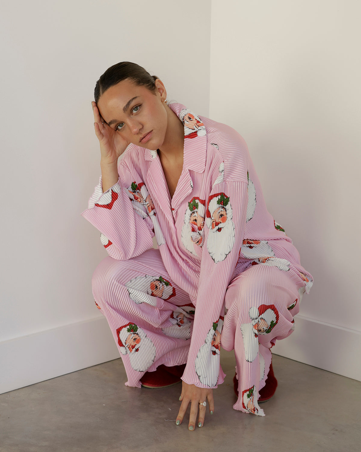 pink and white pinstripe christmas pajama set featuring oversized vintage santa face prints, a notched collar, button-front top and matching wide-leg pants.