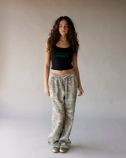 Black cropped tank top with green script graphic, styled with camo sweatpants