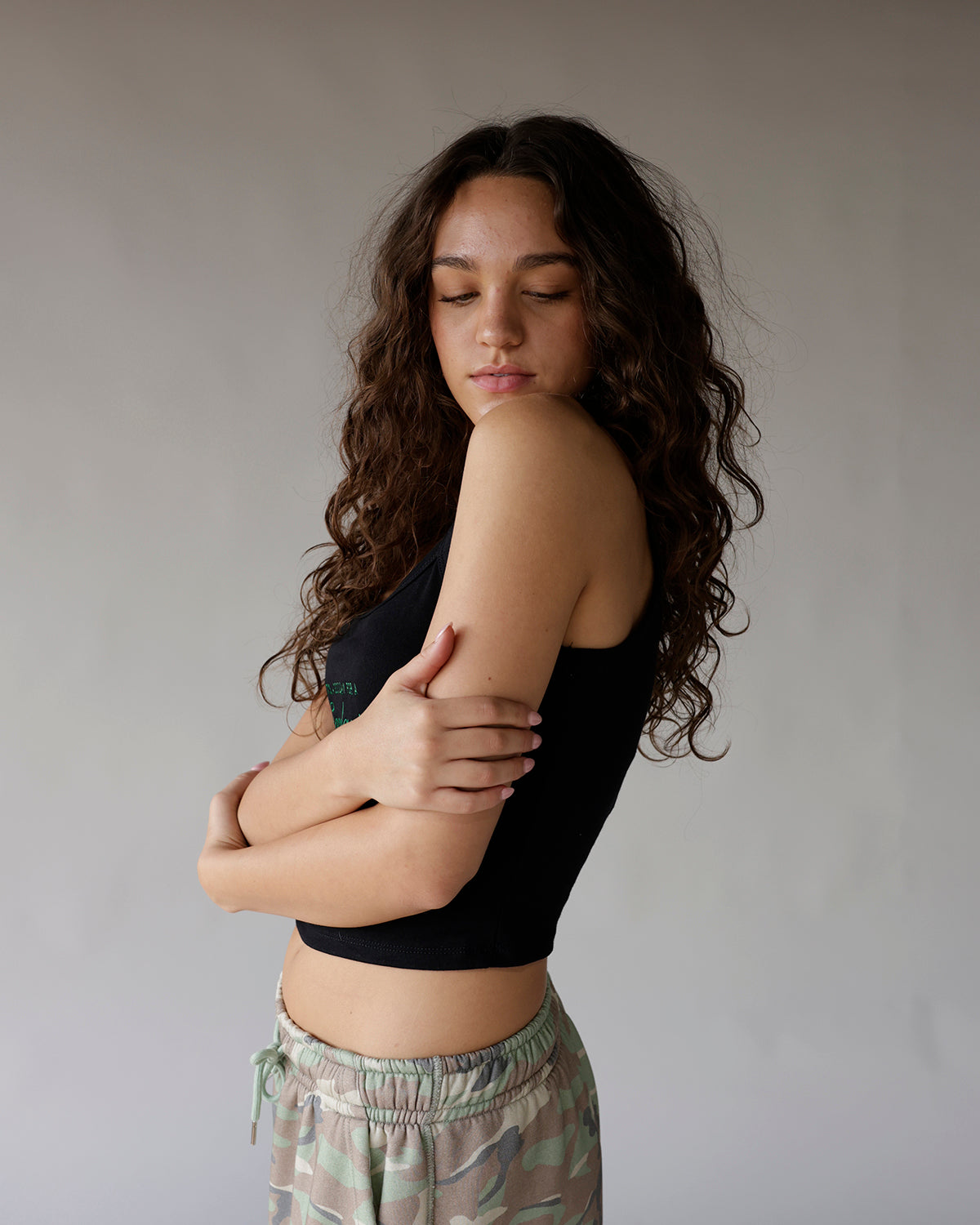 Black cropped sleeveless tank top with small green graphic detail on front