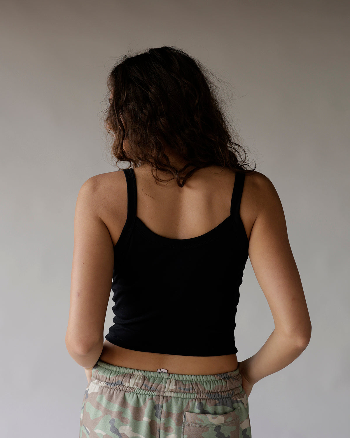 Black ribbed cropped tank top with thin straps, back view