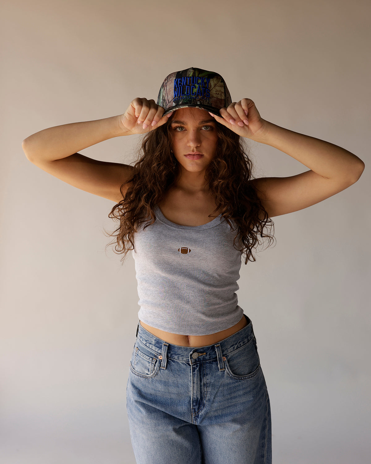 Kentucky Wildcats camo trucker hat with blue embroidered text, worn by model