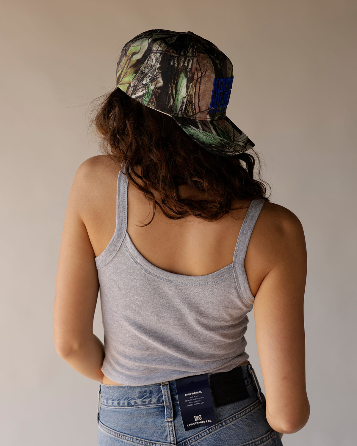 Kentucky Wildcats camo trucker hat with blue embroidered logo, worn backward