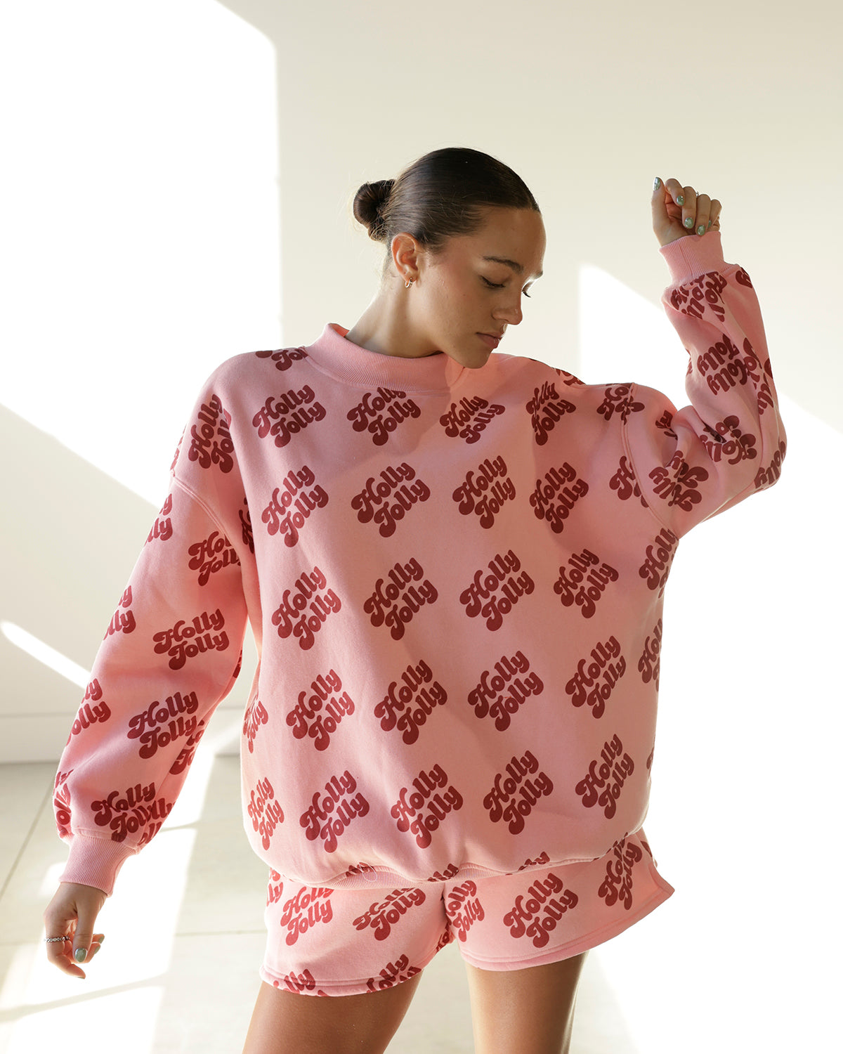 women's pink christmas sweatshirt and shorts set featuring an allover burgundy holly jolly graphic print, oversized crewneck sweatshirt and matching shorts.