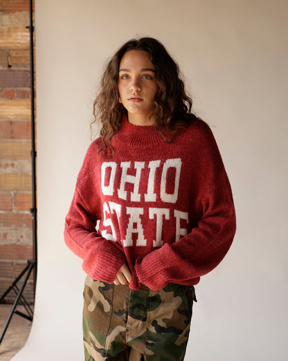 Oversized red knit Ohio State sweater with white lettering, paired with camo pants
