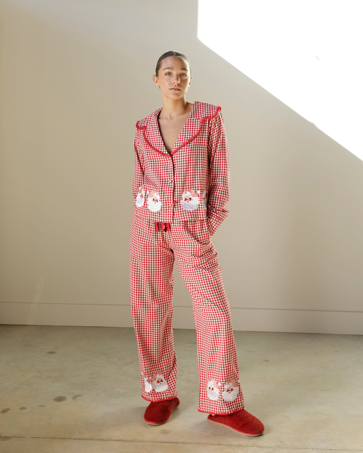 red and white gingham christmas pajama set featuring an oversized collar, vintage santa appliqués, button-front top and matching wide-leg pants.