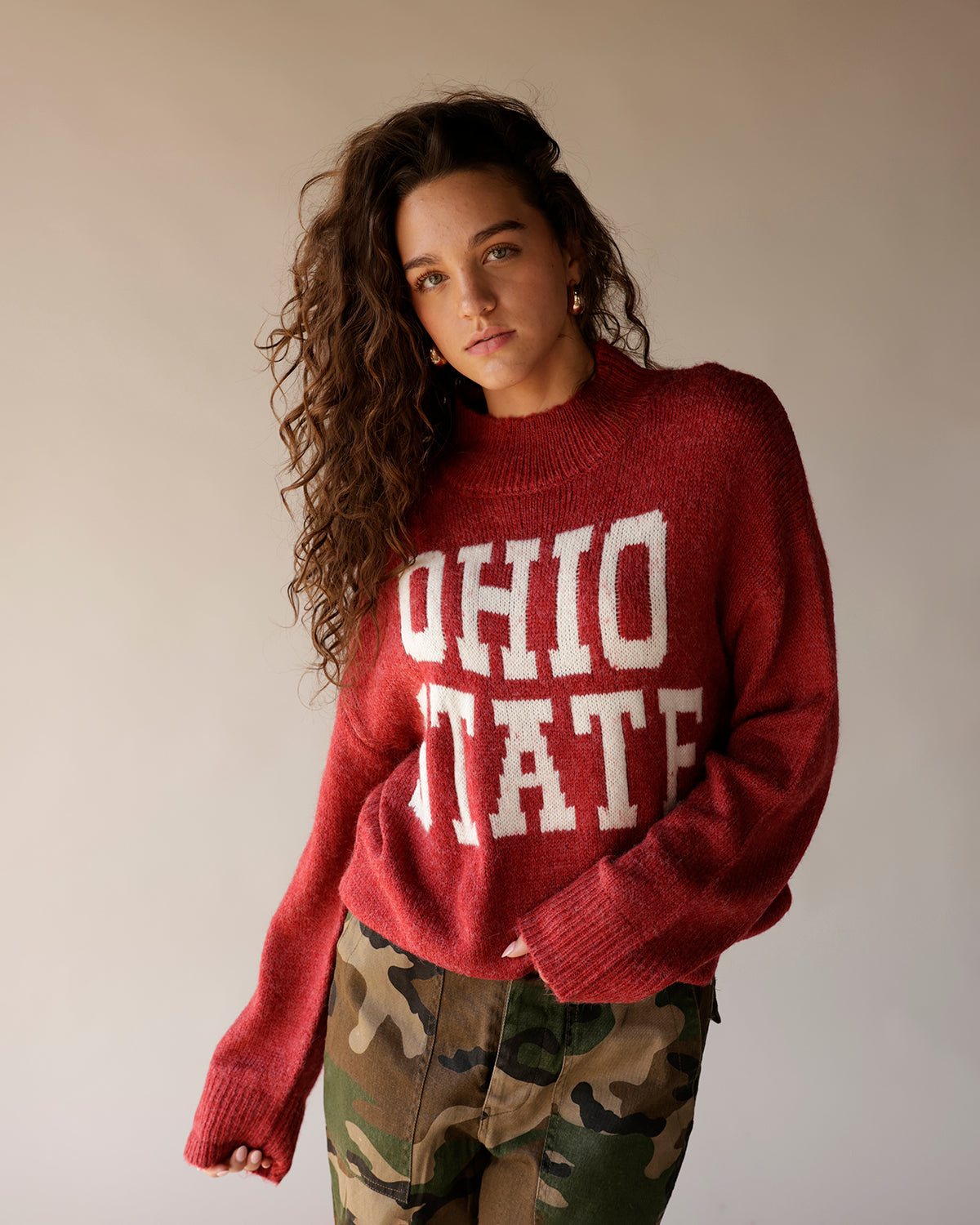 Red knit mock-neck sweater with white Ohio State lettering, worn with camo pants
