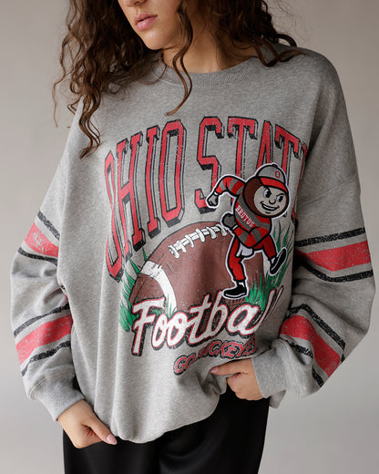 Gray Ohio State Buckeyes football crewneck sweatshirt with Brutus mascot graphic and striped sleeves