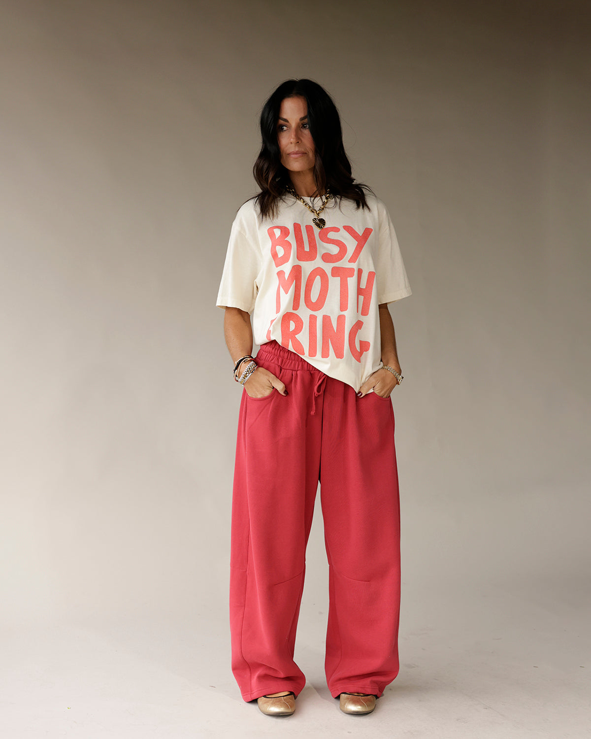 Cream oversized graphic tee with bold red Busy Mothering text print