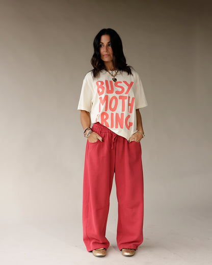 Cream oversized graphic tee with bold red Busy Mothering text print