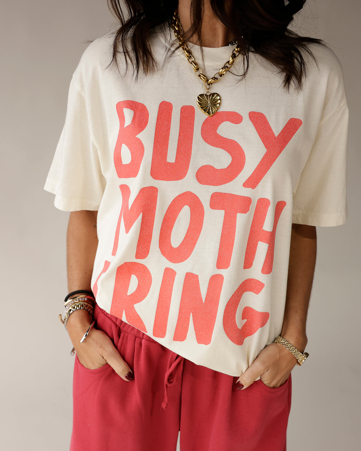 Cream oversized graphic tee with bold pink Busy Mothering text print
