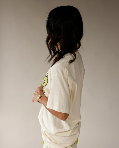 Cream oversized graphic tee with yellow 8 ball print, worn as side profile