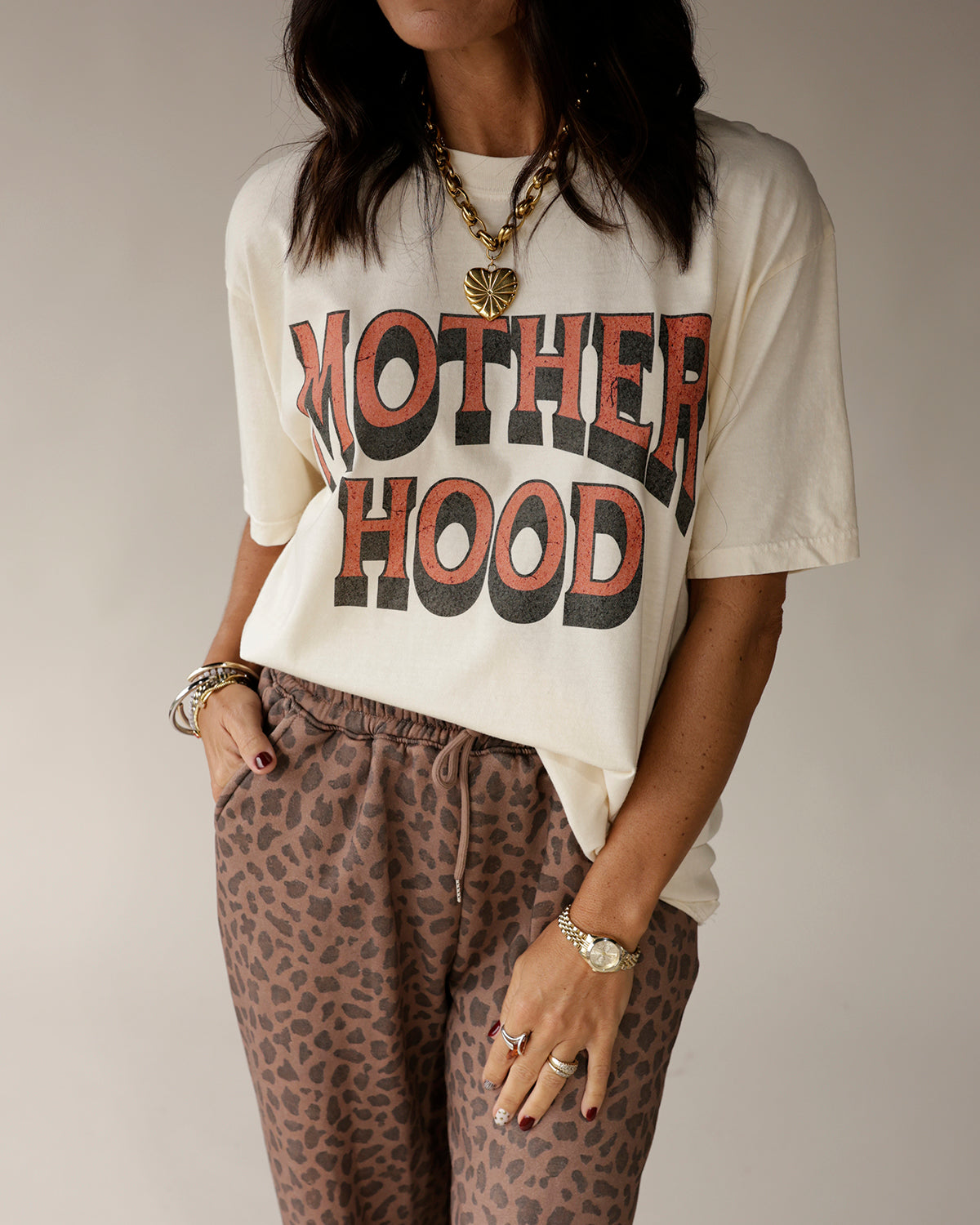 Cream oversized graphic tee with bold MOTHERHOOD print in red and black lettering
