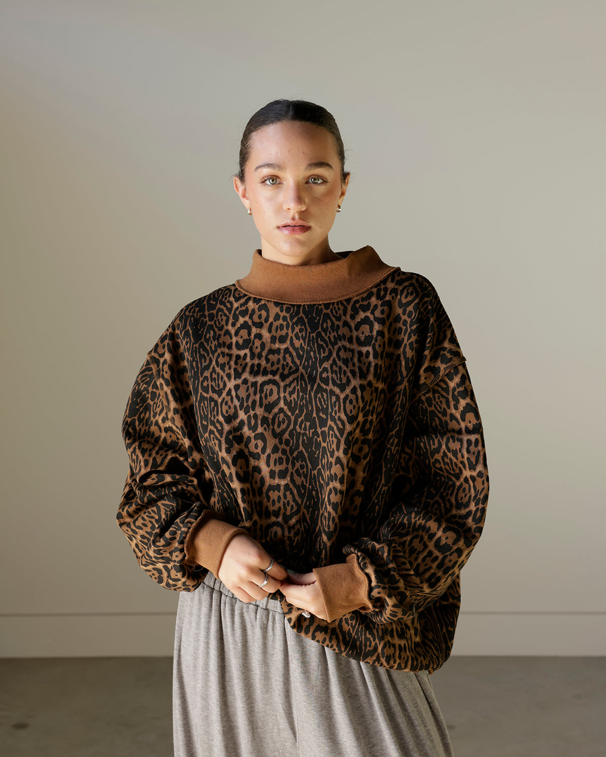 women wearing a brown leopard mockneck sweatshirt with baggy grey pants