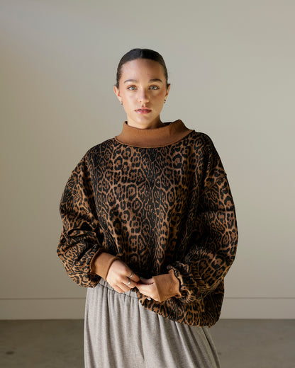 women wearing a brown leopard mockneck sweatshirt with baggy grey pants
