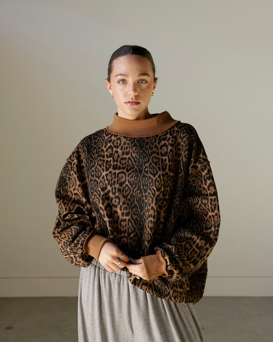 women wearing a brown leopard mockneck sweatshirt with baggy grey pants