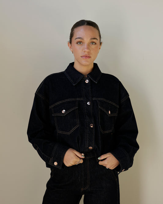 women wearing dark denim jacket with her hair pulled back and wearing dark denim jeans 