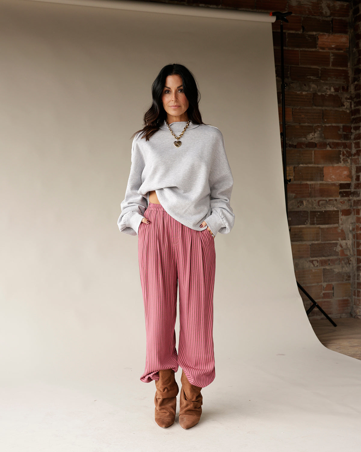 Wide-leg pleated pink striped dressy pants with elastic waist, styled with brown boots